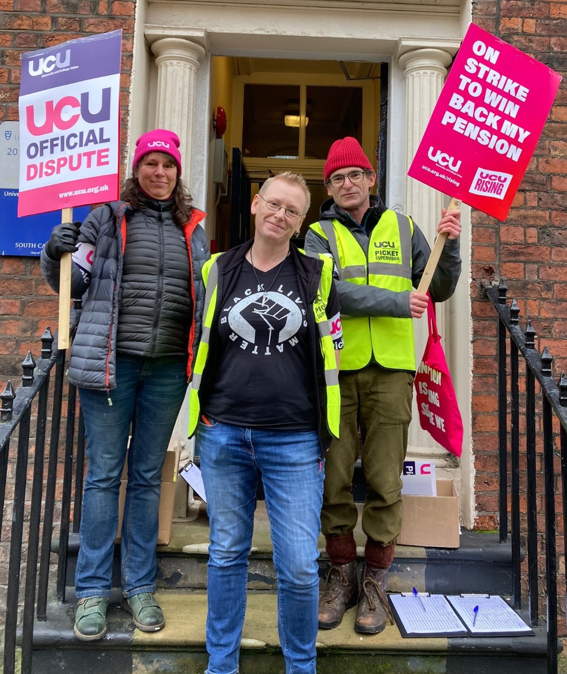 Branch president Peta and members holding placards reading 'UCU official dispute' and 'On strike to win back my pension' outside the UoL UCU office.
